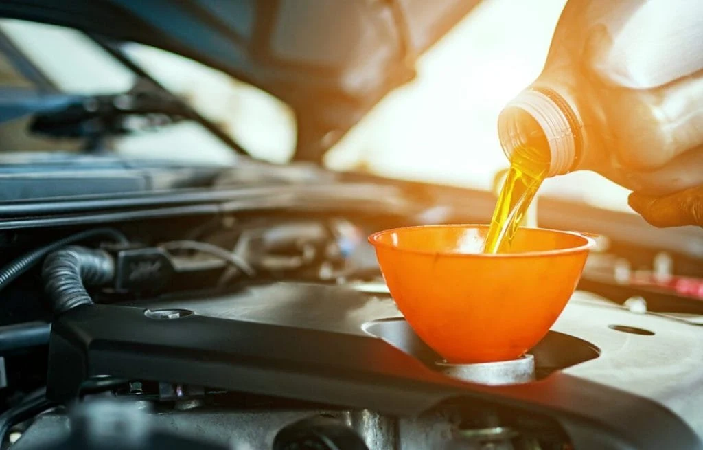 Engine oil being added through a funnel during an oil change