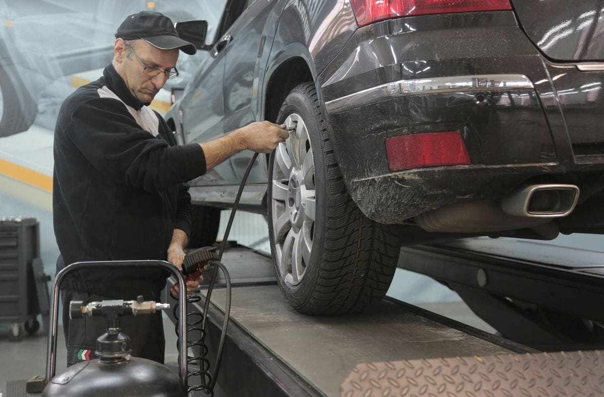 Mechanic adding air to a car tyre in a workshop