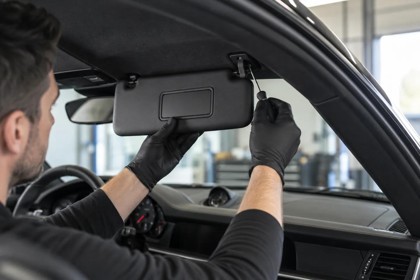 Technician fitting an interior sun visor at its mounting, illustration