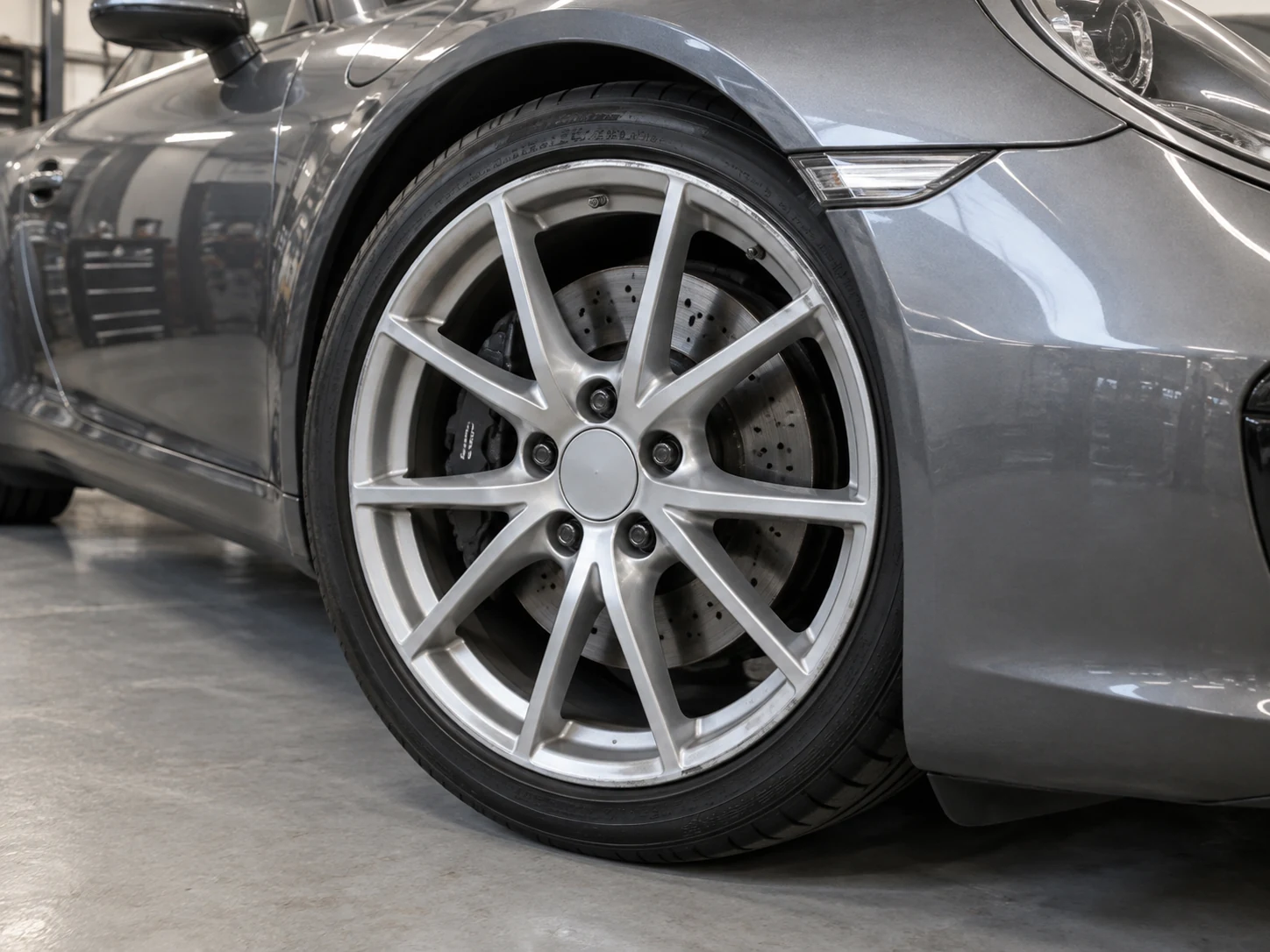 Silver Porsche alloy wheel showing light cosmetic marks around the rim edge
