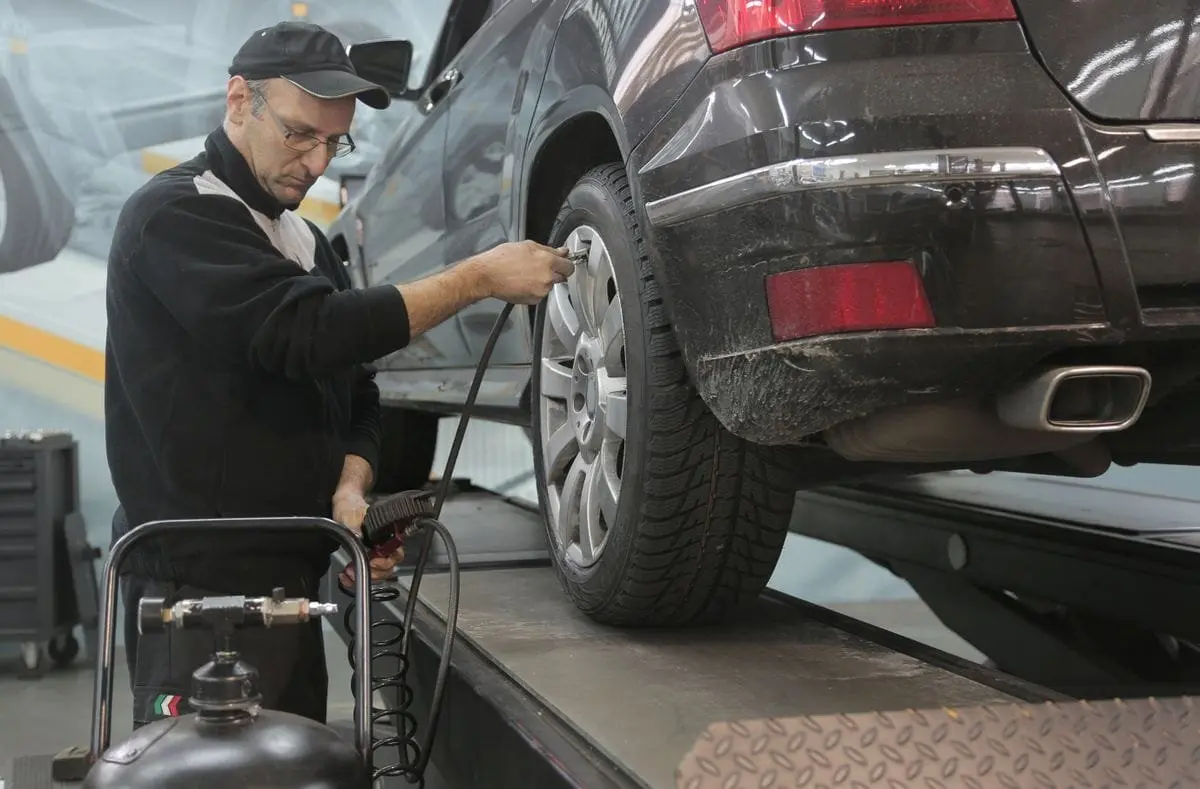Technician checking tyre pressure on a vehicle in a workshop